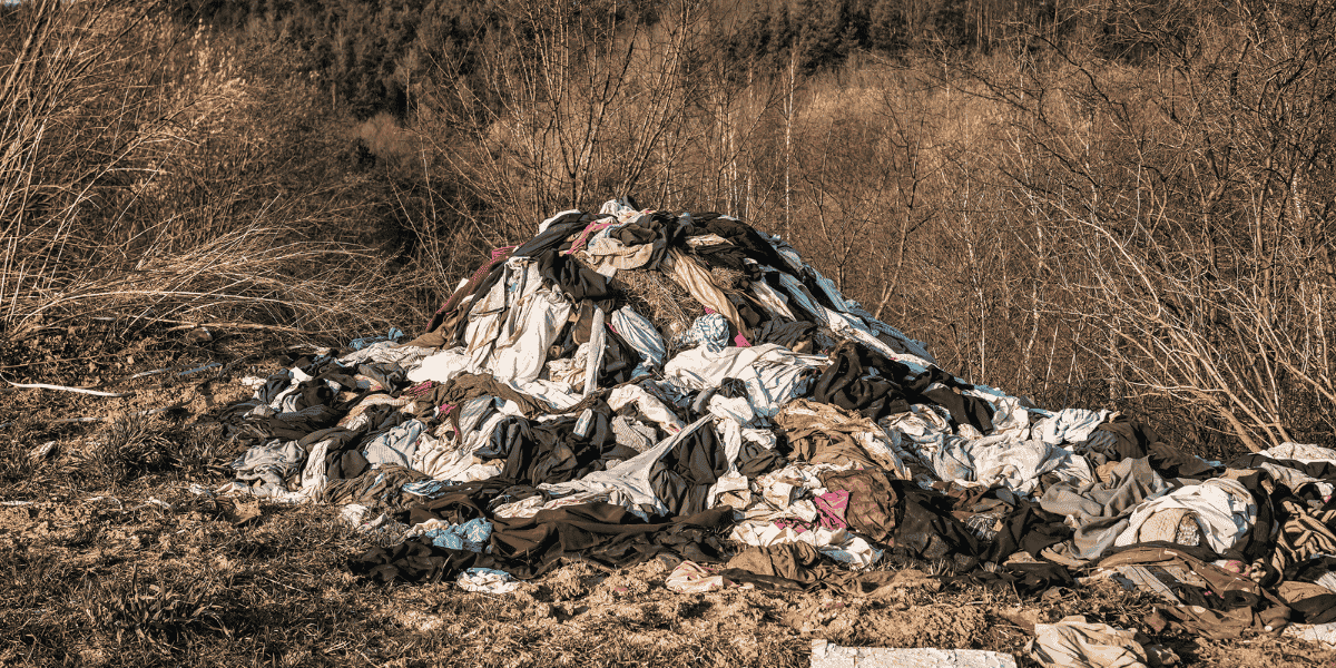 Pile of discarded fast fashion clothing representing textile waste and greenhouse gas emissions